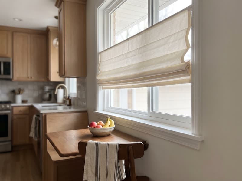 Cream cafe-height roman shade above a kitchen banquette in Smyrna